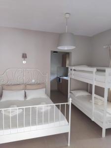a bedroom with two white bunk beds and a kitchen at Smaragdi Studios in Pefkari