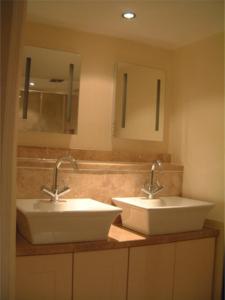 a bathroom with two sinks and two mirrors at Tibbiwell Lodge in Painswick
