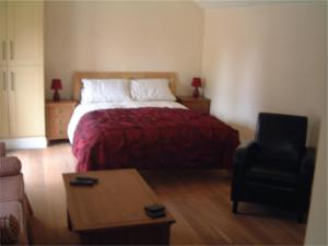 ein Schlafzimmer mit einem Bett mit einer roten Decke und einem Stuhl in der Unterkunft Tibbiwell Lodge in Painswick