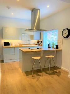 eine Küche mit einer Insel mit zwei Hockern und einer Uhr in der Unterkunft Luxury 2 bed Apartment-Golden Triangle w/ Parking in Norwich