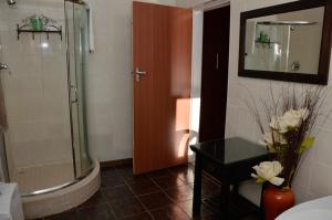 a bathroom with a shower and a vase of flowers at Two Bells Guest House in Bloemfontein