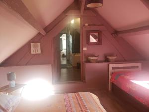 a attic room with a bed and a mirror at Les 2 chaumières avec piscine in Épinay