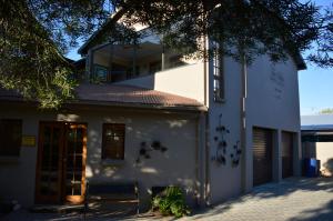 un edificio bianco con una panchina davanti di Two Bells Guest House a Bloemfontein