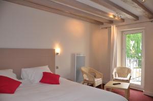 Hotel de la Couronne في إيكس لي بان: غرفة نوم بسرير ابيض ومخدات حمراء ونافذة