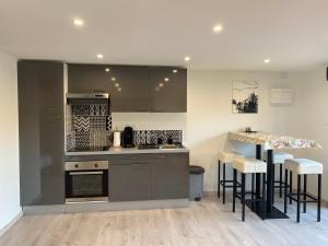 une cuisine avec des placards gris et un comptoir avec des tabourets de bar dans l'établissement Loft lumineux et moderne à Montauban, à Montauban