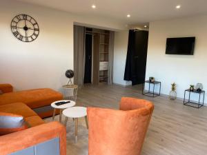 Loft lumineux et moderne à Montauban في مونتوبان: غرفة معيشة مع أريكة وساعة على الحائط