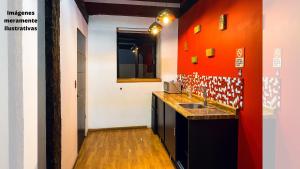 cocina con fregadero y pared roja en Suites Aldama, en Toluca