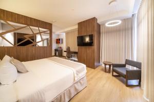 a bedroom with a bed and a chair and a television at Metria Hotel in León