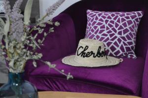 a hat sitting on a purple couch with a vase of flowers at Ambassadeur Hotel - Cherbourg Port de Plaisance in Cherbourg en Cotentin