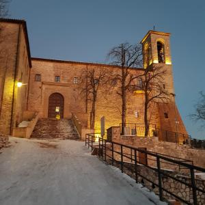 duży ceglany budynek z wieżą zegarową i schodami w obiekcie Appartamento Gattapone 9 w mieście Gubbio
