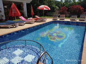 a large swimming pool with chairs and umbrellas at Bluesea Beach Resort in Candolim