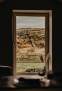 a view of a field through a window at Luxury countryside getaway with wood fired hot tub, Cottage or Shepherds Hut in Gransha