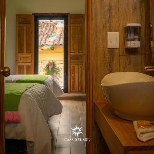 a bathroom with a sink and a bed and a window at Hotel Casa del Sol in San Cristóbal de Las Casas