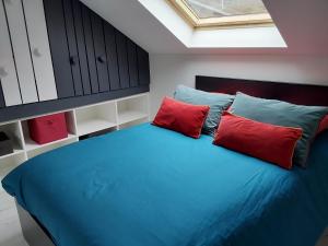 a bedroom with a blue bed with two red pillows at Au Paradis du Loft Joyeux in Willer-sur-Thur