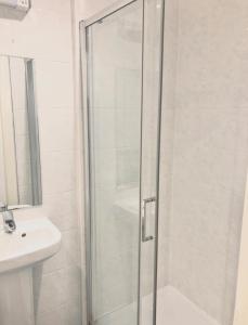a shower with a glass door next to a sink at FoxHouse Studio Apartments in Plymouth