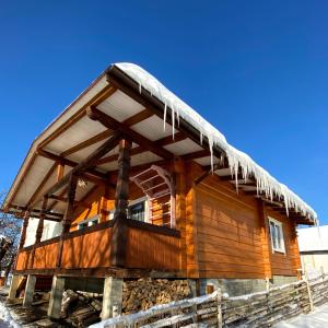 eine Blockhütte mit Eiszapfen auf dem Dach in der Unterkunft Котедж ''Олечка'' in Jaremtsche