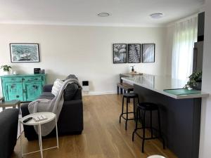 a living room with a black couch and a kitchen at Kiama Palms on Terralong in Kiama