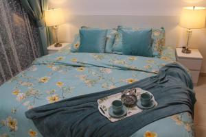 Una cama con una bandeja con dos tazas. en Newly furnished One Bedroom Apartment next to Metro & Beach in Marina Residence, en Dubái