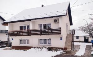 a white house with snow on the roof at Apartman Sofia in Otočac