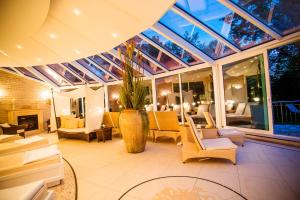 a conservatory with chairs and a vase with a plant at Thermenhotel Quellenhof in Bad Füssing