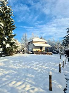 un patio cubierto de nieve con una casa en el fondo en Holiday Home Čarobna Kućica en Pale