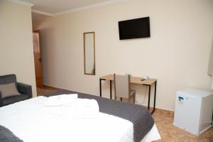 a bedroom with a bed and a desk and a television at Pousada Costa Rielli in Águas de Lindóia