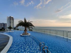 - une piscine avec un palmier à côté de l'océan dans l'établissement Sands Condo SeaView 012, à Pattaya (sud)