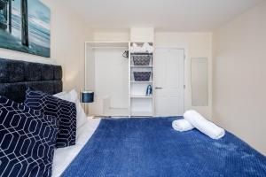 a bedroom with a large bed with a blue blanket at Queens Serviced Apartments - F1 in Watford