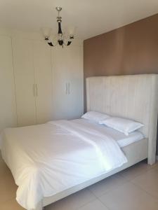 a white bed with white sheets and pillows at Astoria apartments in Nairobi