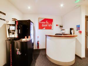 a coffee shop with a counter and a refrigerator at Snooze Hotel in Corby