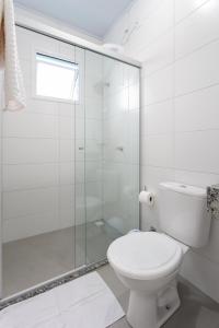 a white bathroom with a toilet and a glass shower at Galileia flat in Santa Maria