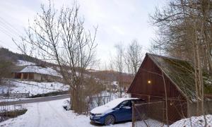 a car parked next to a barn in the snow at PUSTELNIA WODZA in Wisła