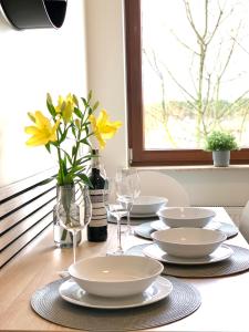 een tafel met borden en glazen en een vaas met gele bloemen bij BALTICUS uroczy apartament w Świnoujściu in Świnoujście