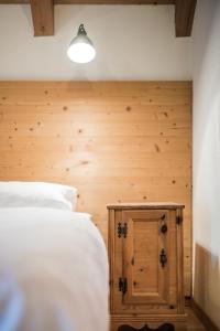 um quarto com uma cama branca e uma parede de madeira em Hotel Hurtmuehle Kronblick em San Lorenzo di Sebato