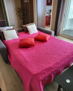 un grande letto rosa con cuscini rossi sopra di T2 classé 4 étoiles avec jardin, piscine, vue mer à Saint-Gilles-les-Bains a Saint-Gilles-les Bains