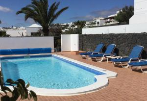 a swimming pool with blue chairs and a wall at Casa Mcelroy in Tías