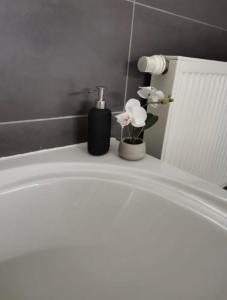 una vasca da bagno bianca con un dispenser di sapone e fiori di LA SUITE 159 a Namur