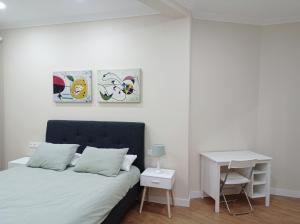 a white bedroom with a bed and a desk at URDAIHOME in Guernica y Luno