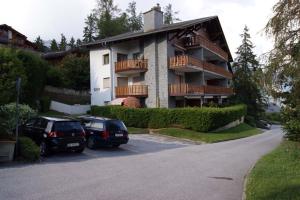 two cars parked in a parking lot in front of a building at Hautes Roches - Magnifique vue sur la montagne in Crans-Montana