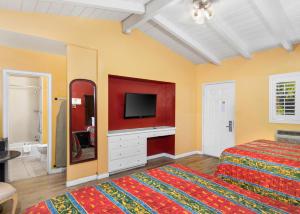 a bedroom with a bed and a tv on the wall at Fallbrook Country Inn in Fallbrook