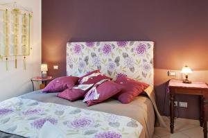 a bed with purple and white pillows in a bedroom at Casa Vacanza IL NIDO in Berbenno di Valtellina