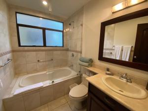 a bathroom with a tub and a toilet and a sink at Monte Carlo Luxury Condominiums in Jacó