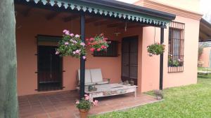 a porch of a house with a bench and flowers at Pampa y Saboya in Villa Elisa