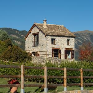 an old stone house behind a wooden fence at Casa Rural "Las Eras" in Fanlo del Valle de Vío