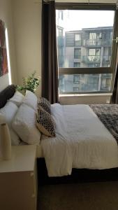 a bedroom with a bed with pillows and a window at Modern city centre 1 bed apartment with gym access & free parking by Lets Relocations in Birmingham