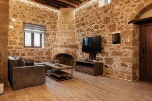 a living room with a stone wall with a couch and a tv at Villa Anaflo in Haraki