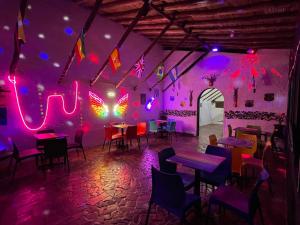 Habitación con mesas, sillas y luces púrpuras. en Club AVIVA Guatavita - Hostel - Restaurante, Disco & Bar, en Guatavita