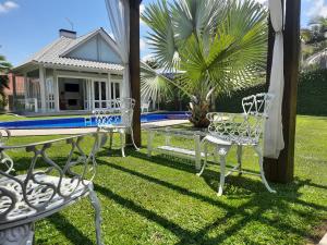 two white chairs and a table in front of a house at Casa da Piscina, Bento Gonçalves - Serra Gaúcha in Bento Gonçalves