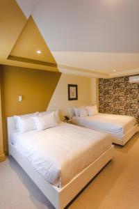 サカテカスにあるMatiana Morelosの壁付きの客室内の白いベッド2台