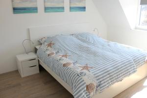 ein Bett mit einer blau-weißen gestreiften Bettdecke und zwei Seestern in der Unterkunft Reihenhaus Mittelweg 37b in Grömitz